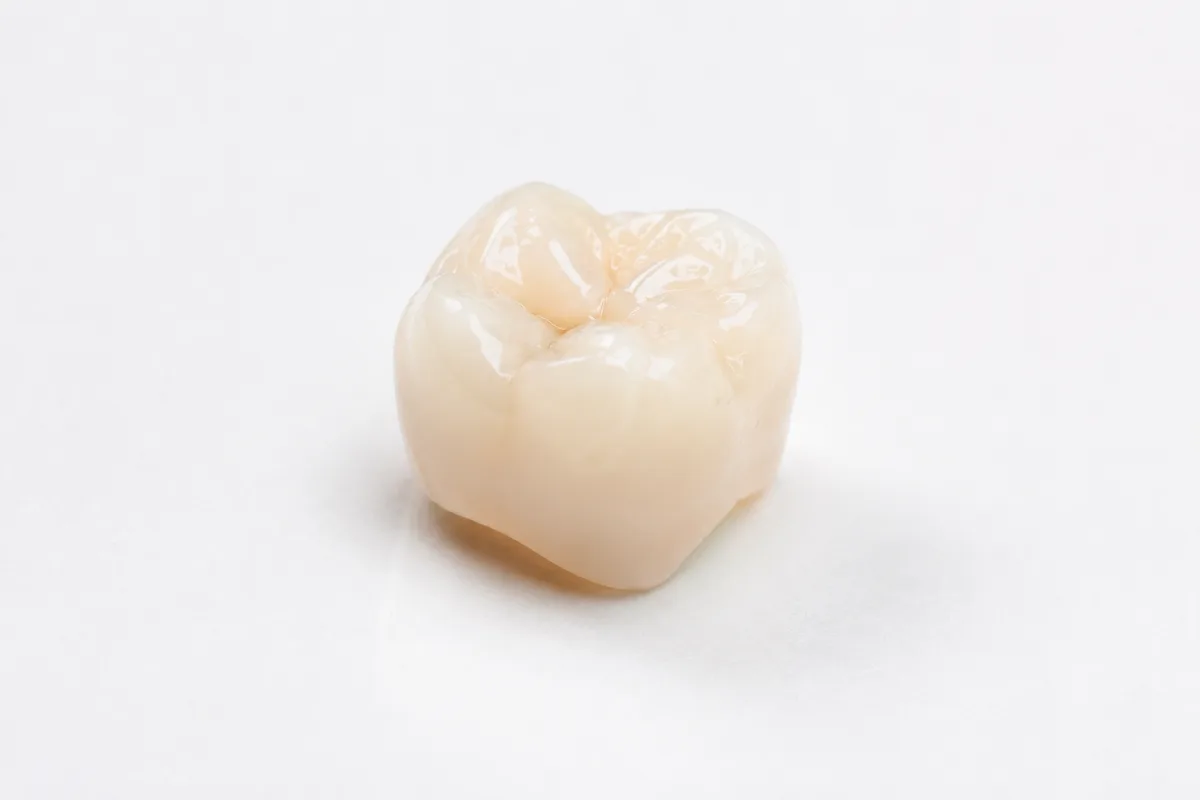 Porcelain dental crown on white surface