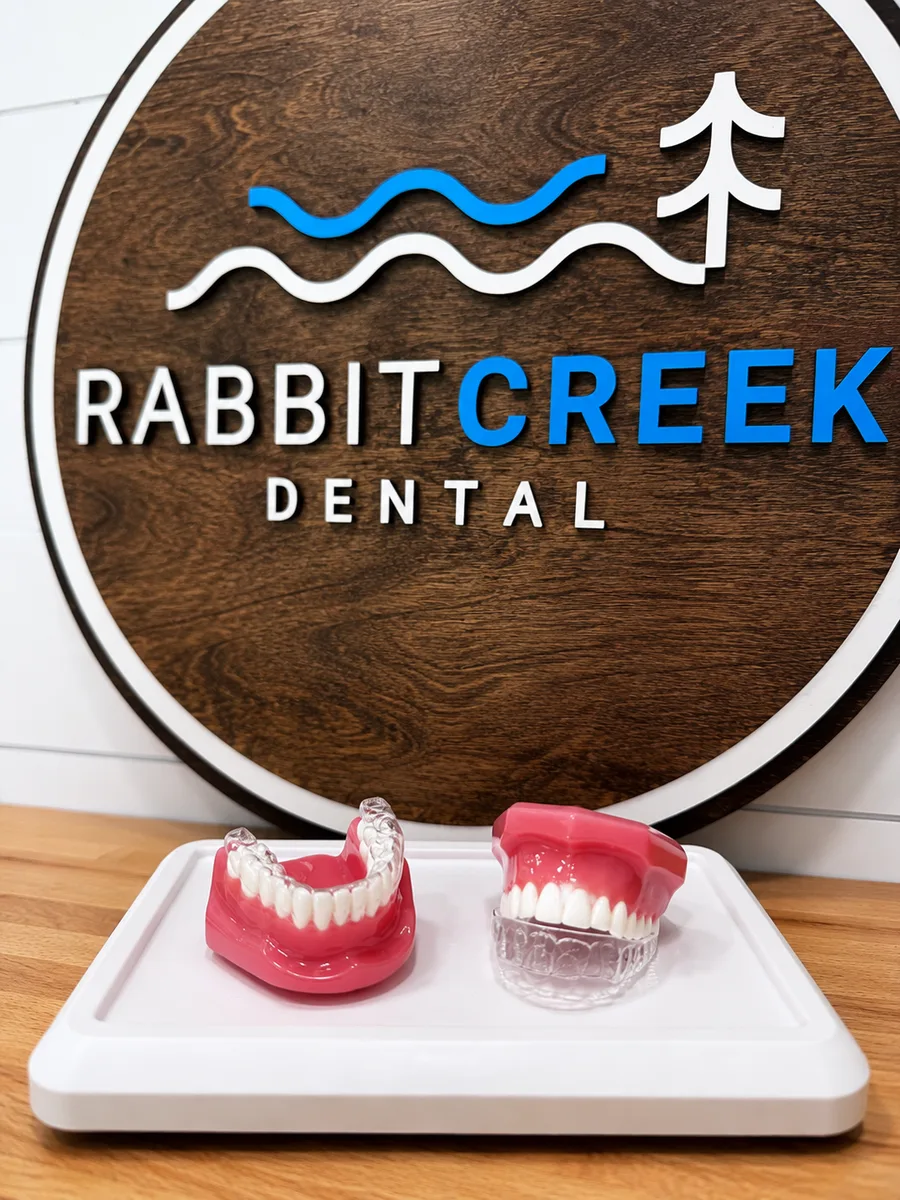 SureSmile clear aligner tray next to traditional metal braces at Rabbit Creek Dental in Mobile, AL