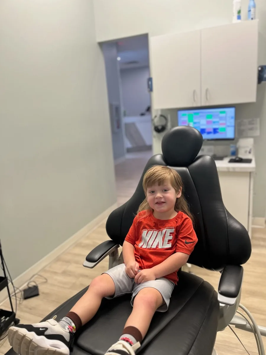 A young child sitting comfortably and smiling in the dental chair at Rabbit Creek Dental in Mobile, Alabama