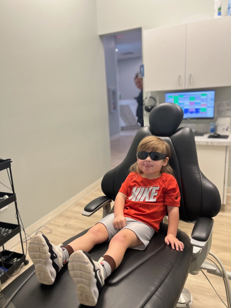 A young patient wearing sunglasses and relaxing in the dental chair at Rabbit Creek Dental
