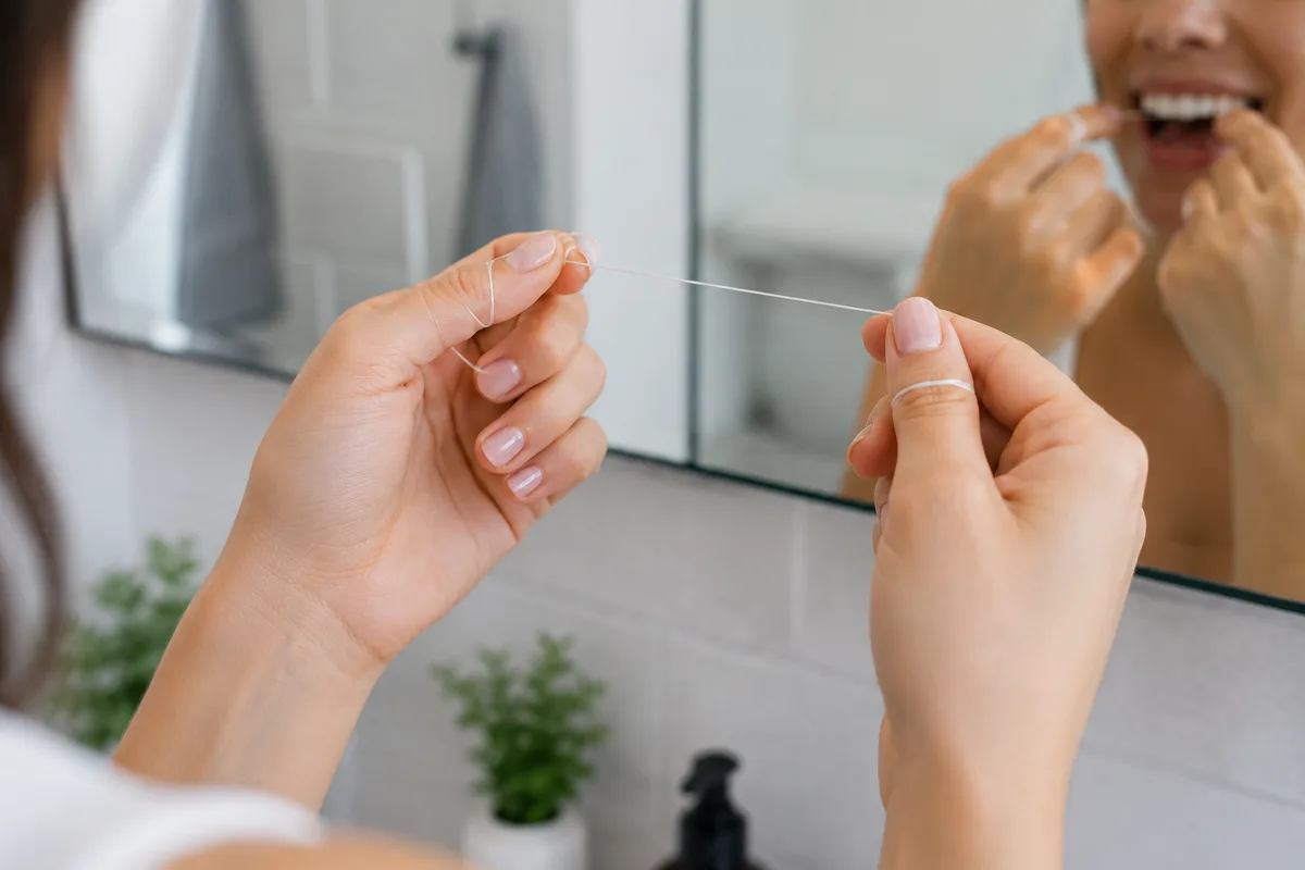 Person flossing between teeth using correct technique at Rabbit Creek Dental in Mobile, AL